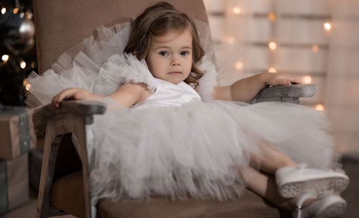 girl wearing white frock is sitting on chair