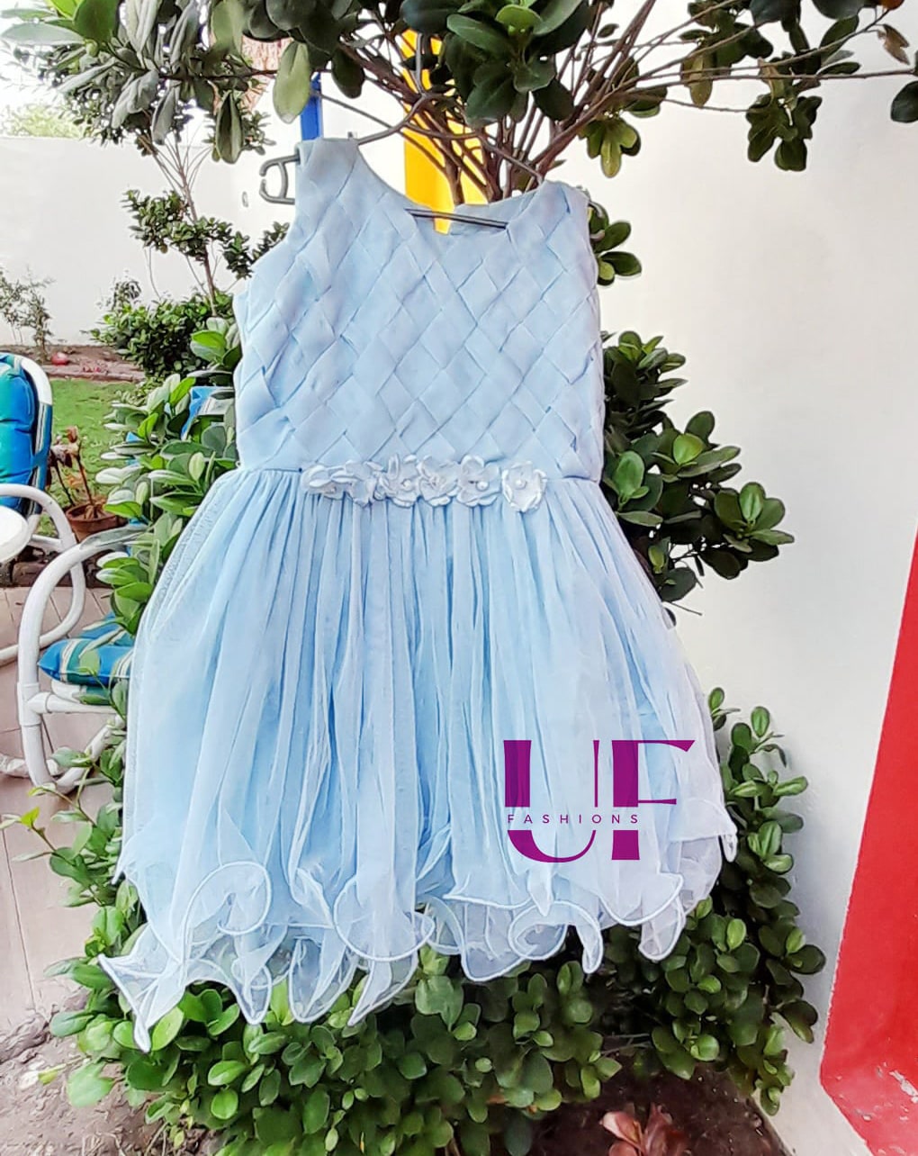 sky colored baby frock hanged on a tree